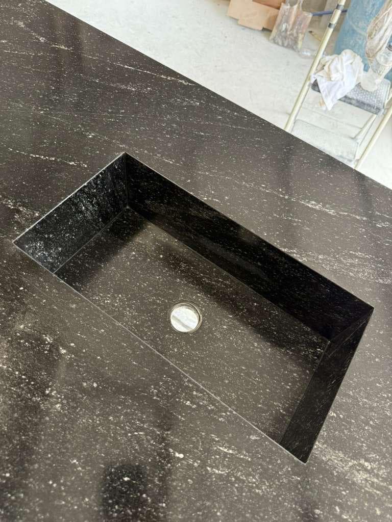 Custom trough sink fabricated from black leathered granite slab