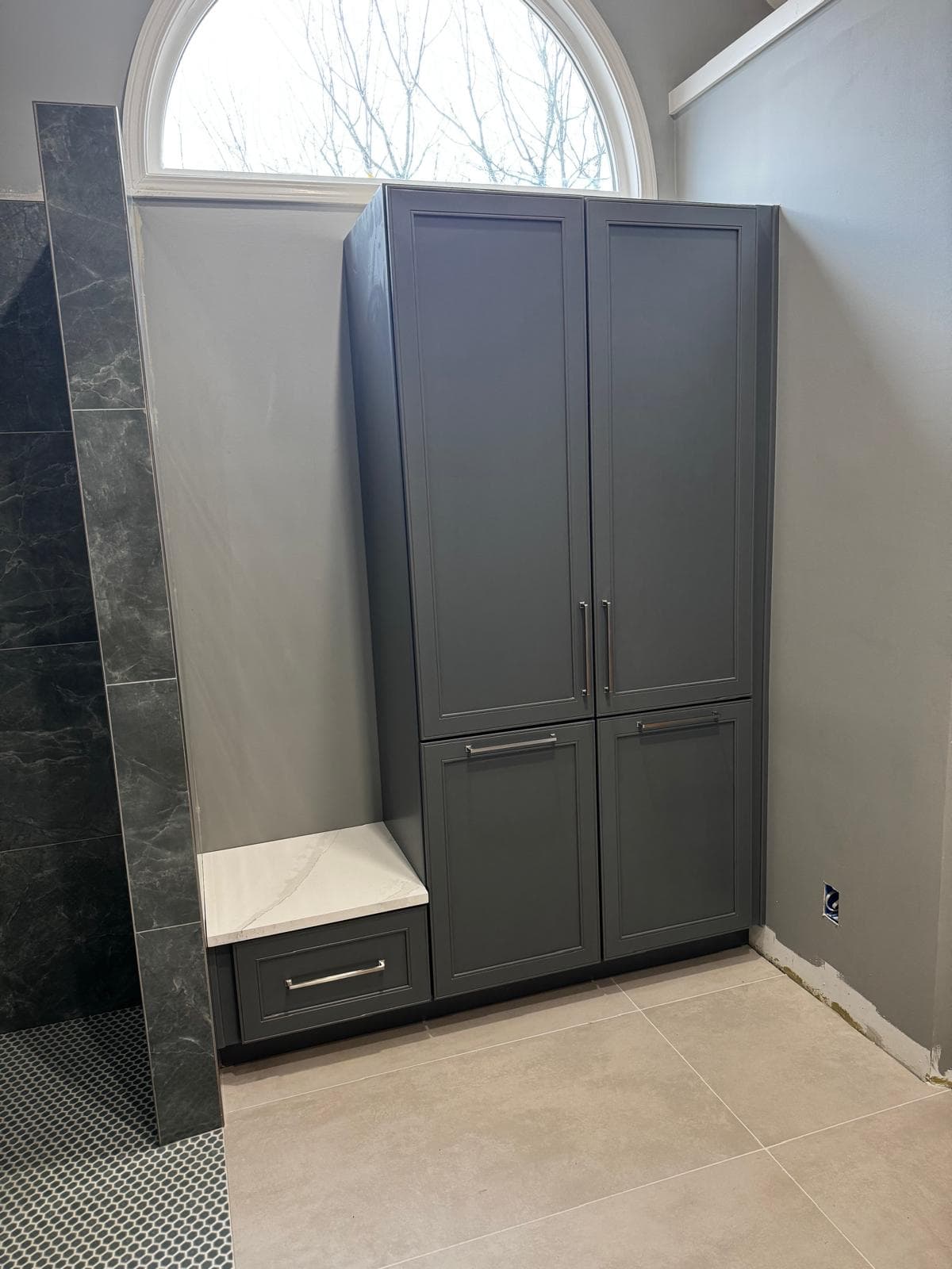 Built-in shower bench with quartz top beside gray linen tower cabinet, Atlanta, GA
