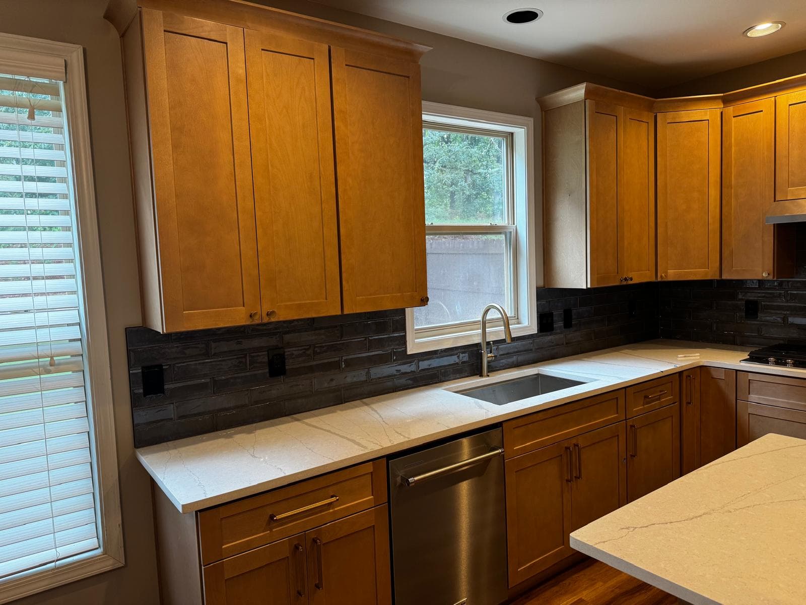 Honey oak kitchen cabinets with black subway tile backsplash and quartz countertops, Atlanta, GA
