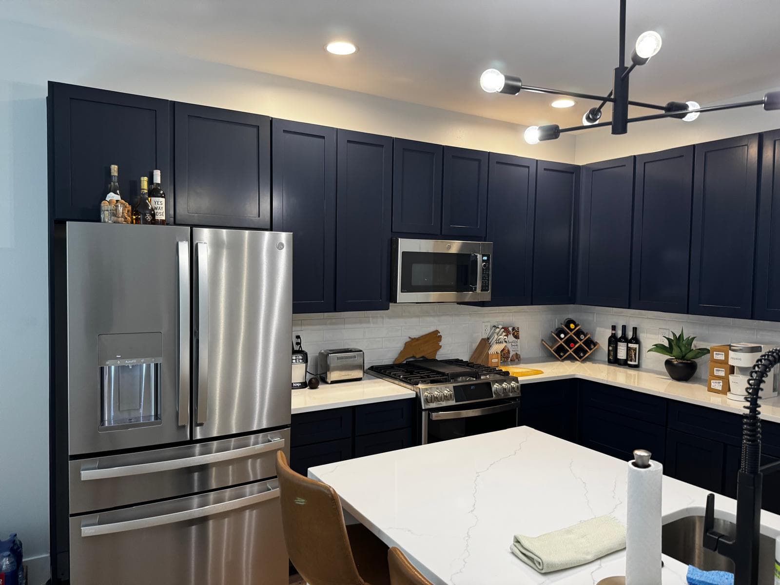 Navy blue kitchen cabinets and quartz island under pendant lighting, Atlanta, GA