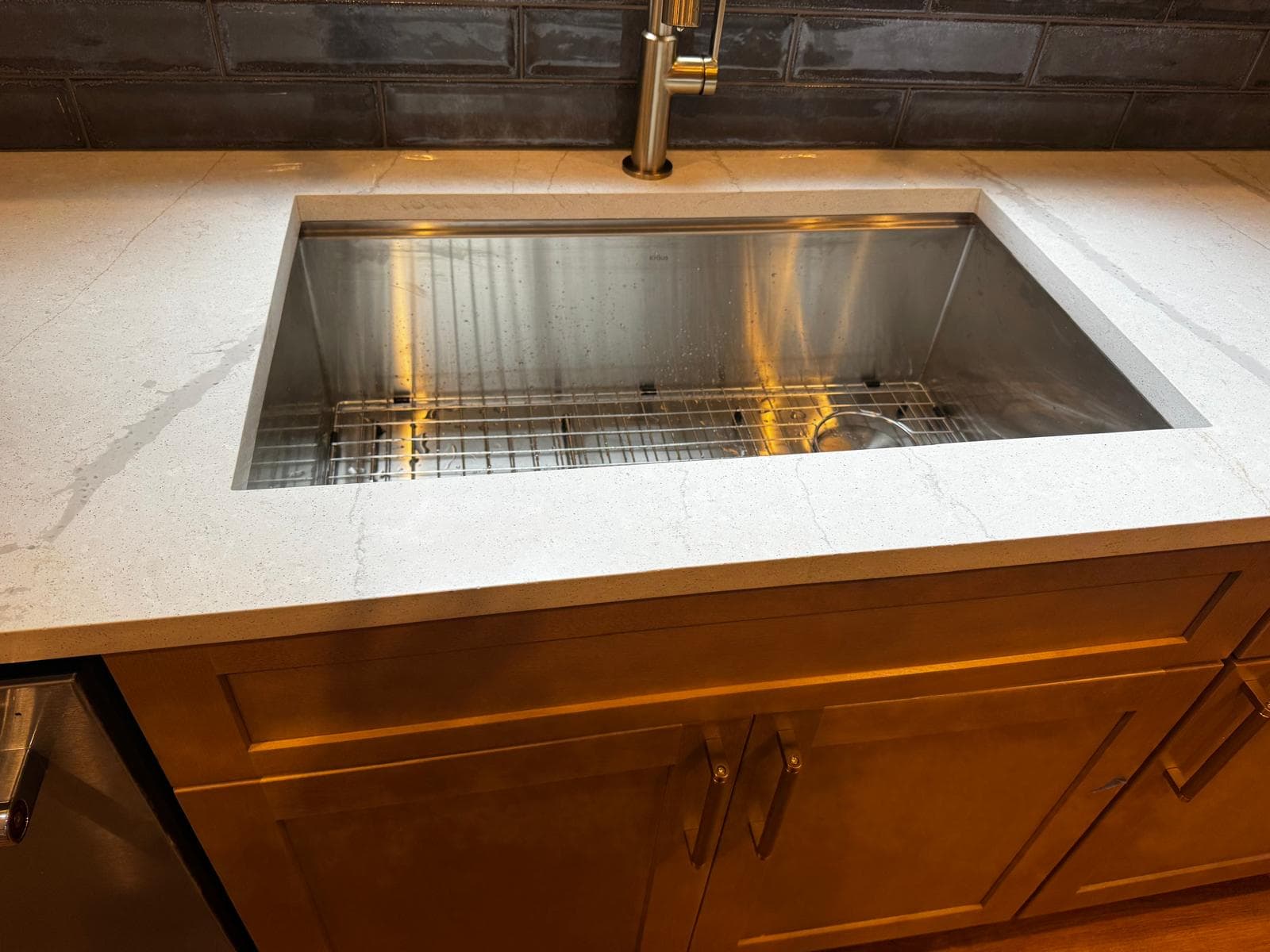 Stainless steel sink set in white quartz countertop with oak cabinets, Atlanta, GA