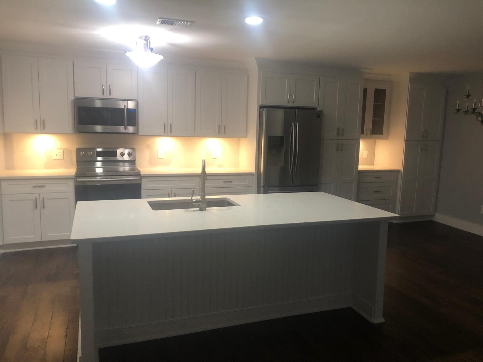 White kitchen cabinets with quartz island over dark hardwood flooring, Atlanta, GA