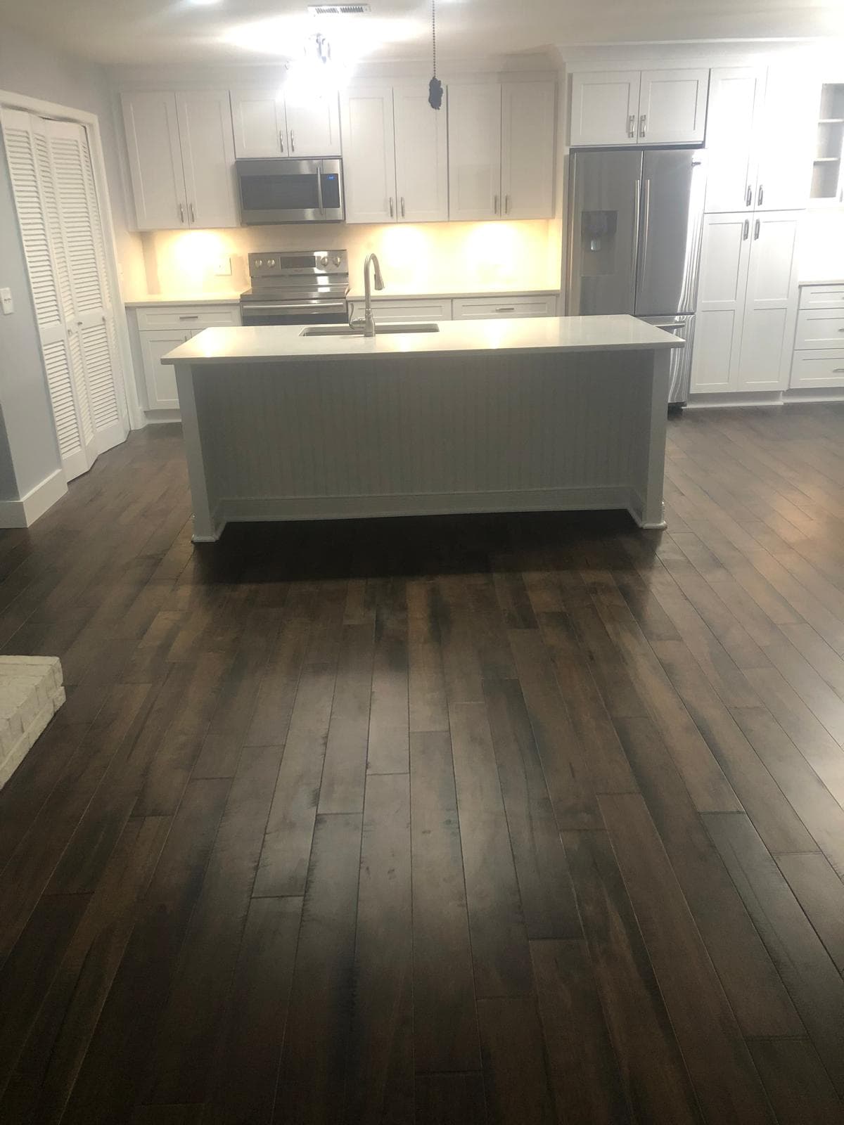 Quartz kitchen island in open concept living space with white cabinets, Atlanta, GA