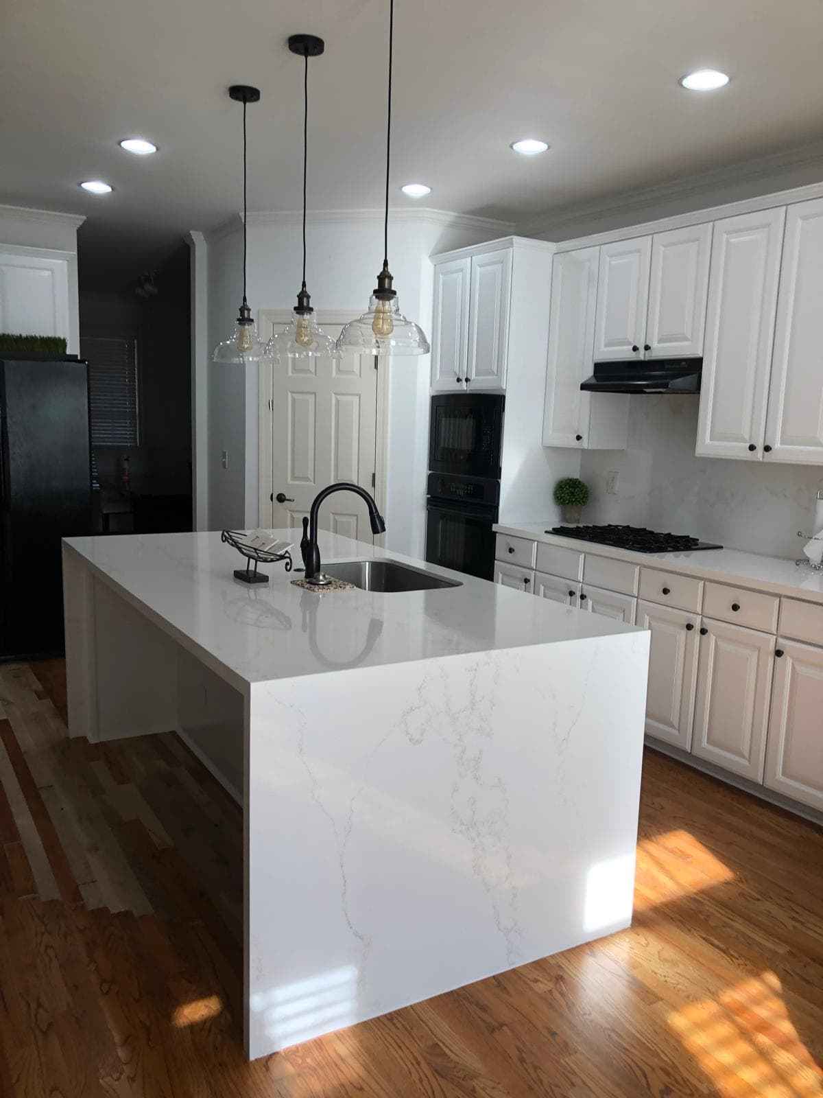 White kitchen cabinets under glass pendant lighting with black appliances, Atlanta, GA