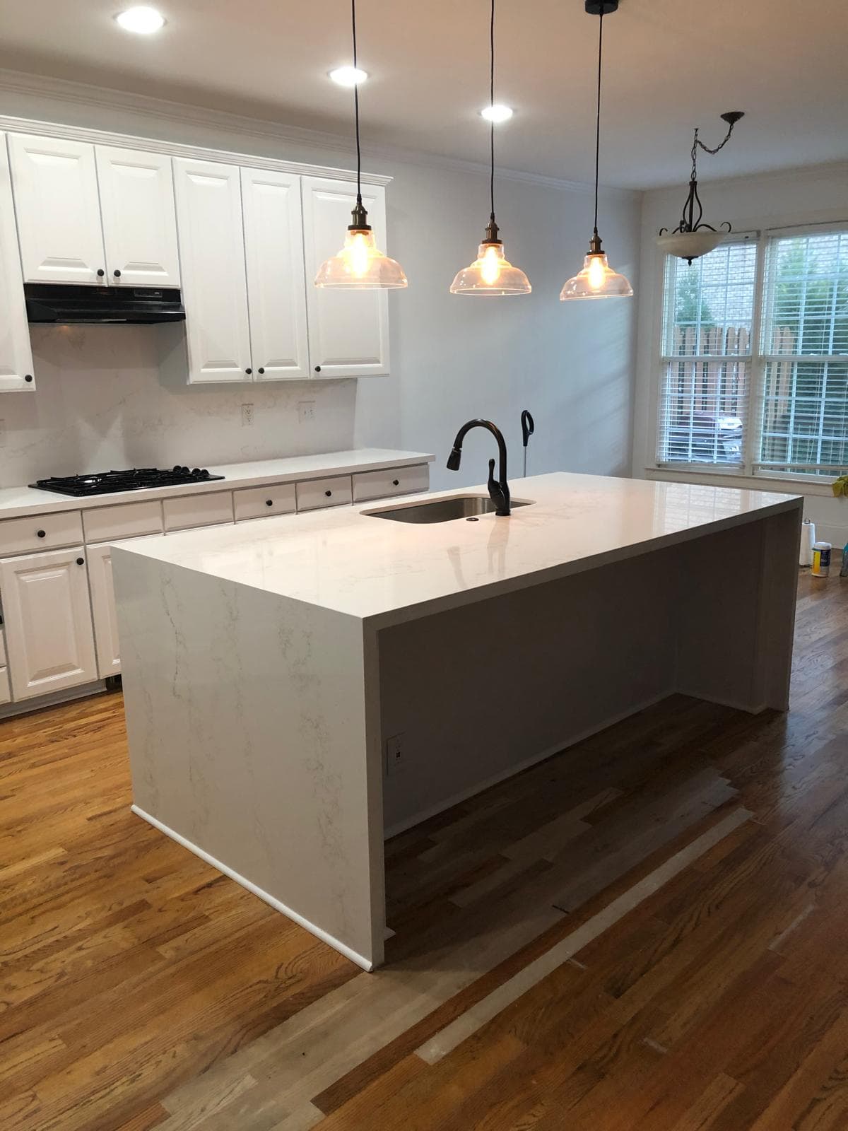 White raised-panel kitchen cabinets with black appliances and quartz countertops, Atlanta, GA